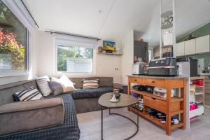 a living room with a couch and a table at Mobilhome - Piscine - Premium in Erdeven +14 photos