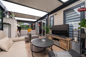a living room with a couch and a tv at Mobilhome - Piscine - Premium in Erdeven