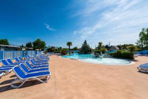 a group of lounge chairs sitting next to a swimming pool at Mobilhome - Piscine - Premium in Erdeven