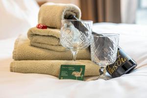 a bed with two wine glasses and a pile of towels at App Kronplatz Villa Colli in Valdaora