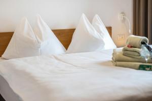 a white bed with white pillows and towels on it at App Kronplatz Villa Colli in Valdaora