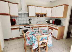 a kitchen with a table and chairs and a kitchen with white cabinets at Maison du centre - ruelle calme in La Tranche-sur-Mer