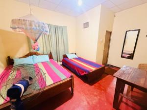 a bedroom with two beds and a fan at C&C Holiday Home in Nikawatawana