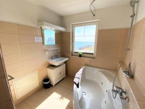 a bathroom with a tub and a sink at Strand Hus by Seeblick Ferien in Olpenitz +23 photos