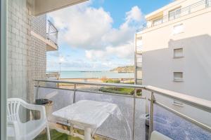 a balcony with a white chair and a view of the beach at Appartement Le Rial - Erquy in Erquy