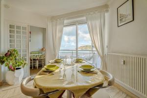 a dining room with a table and a large window at Appartement Le Rial - Erquy in Erquy
