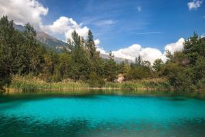 a large blue lake in the middle of a forest at Appartamento Bareu Mountain View - Happy Rentals in Sauze dʼOulx +21 photos