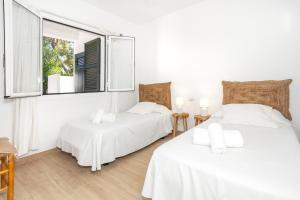 two beds in a white room with two windows at Villa Kassiopea in Cala Blanca +21 photos