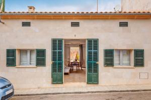 a house with green shutters and a table at Es Pop Nou in Sa Ràpita