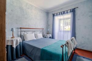 a bedroom with a bed with a blue blanket and a window at Casa da Quinta da Castanheira in Cepões