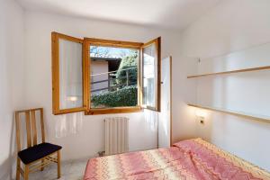 a bedroom with a bed and a window and a chair at Villaggio Colombo V3 comfort in Marina di Andora +26 photos