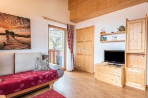 a living room with a red couch and a tv at Huberhof App Rubens in Feldthurns