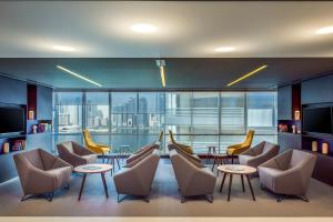 The Act Hotel Sharjah في الشارقة: لوبي فيه كراسي وطاولات ونافذة كبيرة