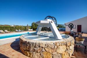 a fountain in a stone wall next to a swimming pool at Villa Oliva Al ii in Moncarapacho