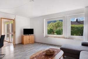 a living room with a couch and a tv and two windows at Haus Reiser in Alpirsbach