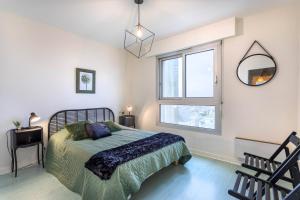 a bedroom with a bed and a window and a mirror at La Houle, appartement face mer in Les Sables-d'Olonne