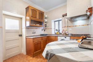 a kitchen with wooden cabinets and a sink and a table at Casinha Da Aldeia in Cela Velha