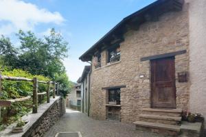 a stone building with a wooden door on a street at Casa Pollicina in Margno