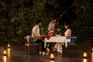 a group of people sitting at a table at night at Wayanad Wild - A CGH Earth Experience in Vythiri
