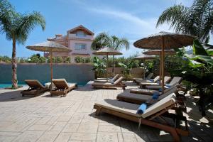 a group of lounge chairs and umbrellas next to a pool at Villa Dionysia Studio S5 in Alikanas
