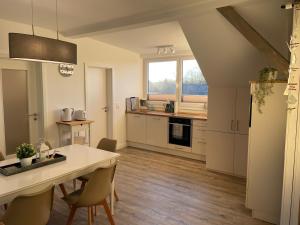 a kitchen with white cabinets and a table with chairs at Ferienwohnung Ankerleicht in Steinbergkirche