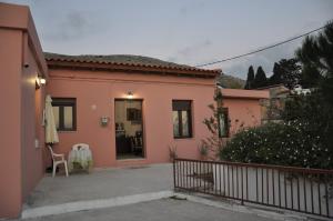 a small pink house with a table and a chair at House For Rent In Apostolous in Apóstoloi