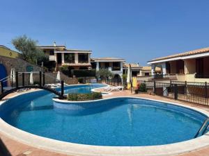 a large swimming pool with blue water in a yard at Dimora Frau in Villasimius