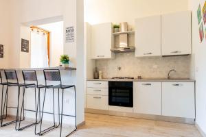 a kitchen with white cabinets and bar stools at Dimora Frau in Villasimius