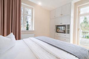 a white bedroom with a bed and a tv at Villa Gruner Nr 13 in Zinnowitz