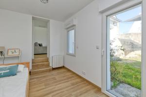 a bedroom with white walls and a large window at Maisons de Saint Guenolé in Batz-sur-Mer