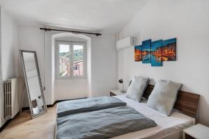 a white bedroom with a bed and a mirror at Casa Leah in Imperia