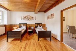 two beds in a room with wooden floors at Restaurant Fewo Golsong in Thaleischweiler-Fröschen