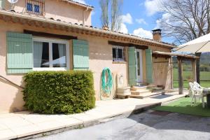 a house with green shutters and a patio at Villa la Myreclose in Saint-Auban