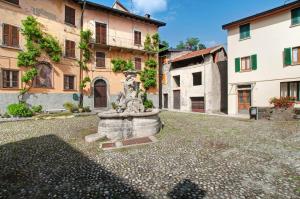 a fountain in the middle of a courtyard with buildings at Thari House Como Lake in Naggio