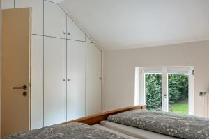 a bedroom with white cabinets and a window at Ferienwohnung Flut am Weserstrand in Sandstedt