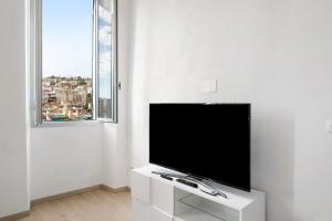 a flat screen tv in a white room with a window at Domus Madonnina in Sanremo