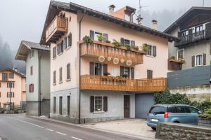 a house with balconies and a car parked on a street at Appartamento Collini in Spiazzo