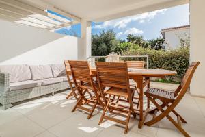 a wooden table and chairs on a patio with a couch at Cormorani appartamento N 5 in Golfo Aranci