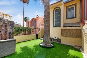 a house with a green yard with a palm tree at Santa Ana 23 in Playa del Ingles