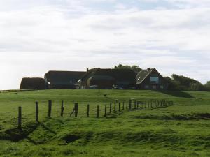 a field with a fence in front of a house at Fewo Nordseeblick in Langeneß
