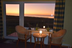 a room with a window with two chairs and a table with a candle at Fewo Nordseeblick in Langeneß