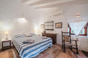 a bedroom with a bed and a chair and a window at Se Teulere in Fornalutx