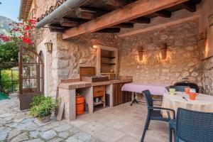 a patio with a table and chairs and a stone wall at Se Teulere in Fornalutx +17 photos