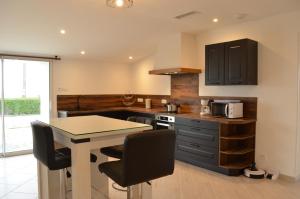 a kitchen with black cabinets and a table with chairs at Gîte les 2 Fontaines in Marans