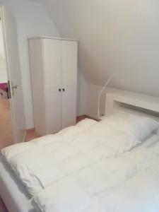 a bedroom with a white bed and a cabinet at Ferienwohnung Loewe in Plau am See +6 photos