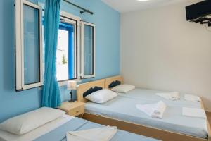 two beds in a room with two windows at Studios Ninemia Serifos 5 in Livadi