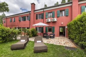 a building with two tables and an umbrella in the yard at Tenuta Ca' Zen - Cottage Casetta in Taglio di Po