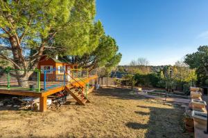 a playground with a play house and a tree at Masia Can Divi in La Ametlla