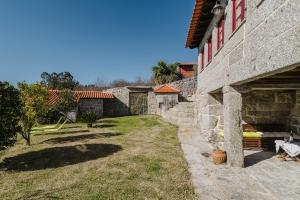 a stone house with a yard next to a building at Cantinho da Tilde in Fafe