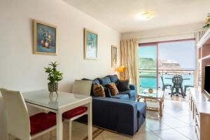 a living room with a blue couch and a table at Su Eminencia in Mogán